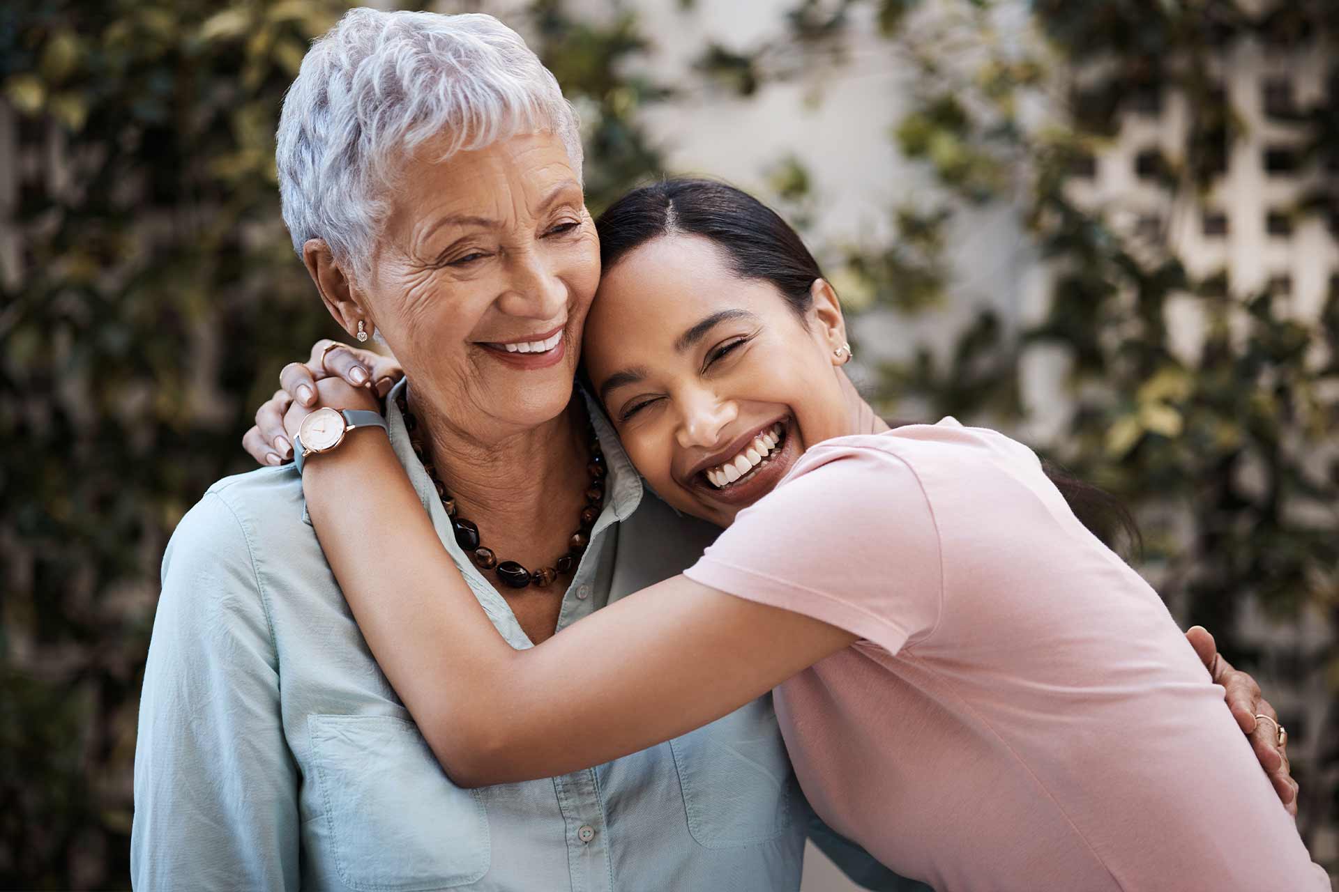 Spanish woman smiling and hugging a mother figure outside